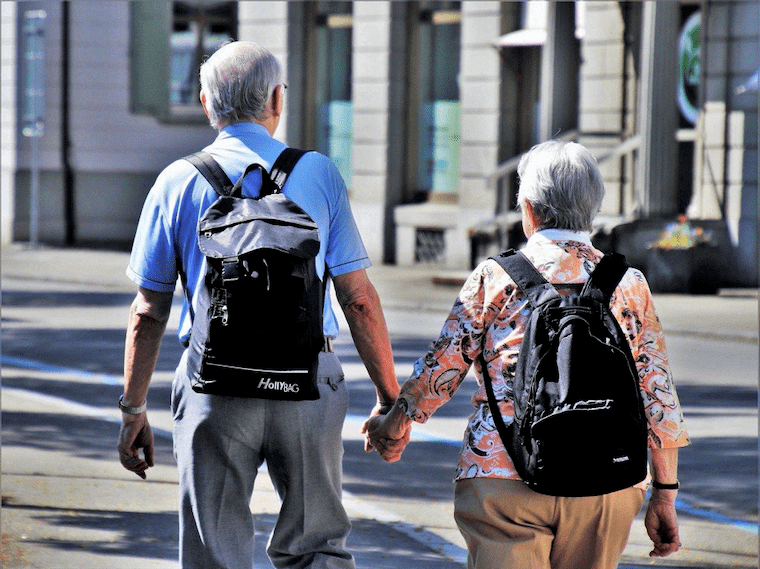 街を手をつないで歩く高齢者夫婦